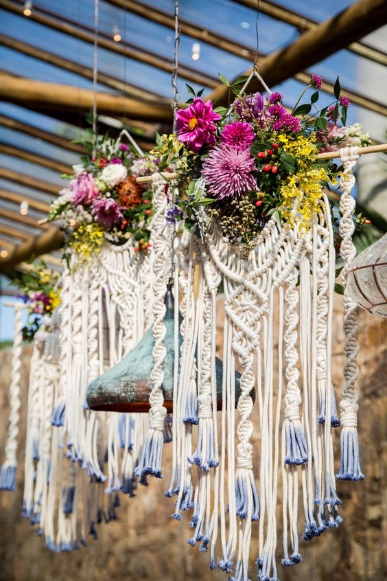 Peças de macramê suspensas com flores coloridas e franjas tingidas de azul